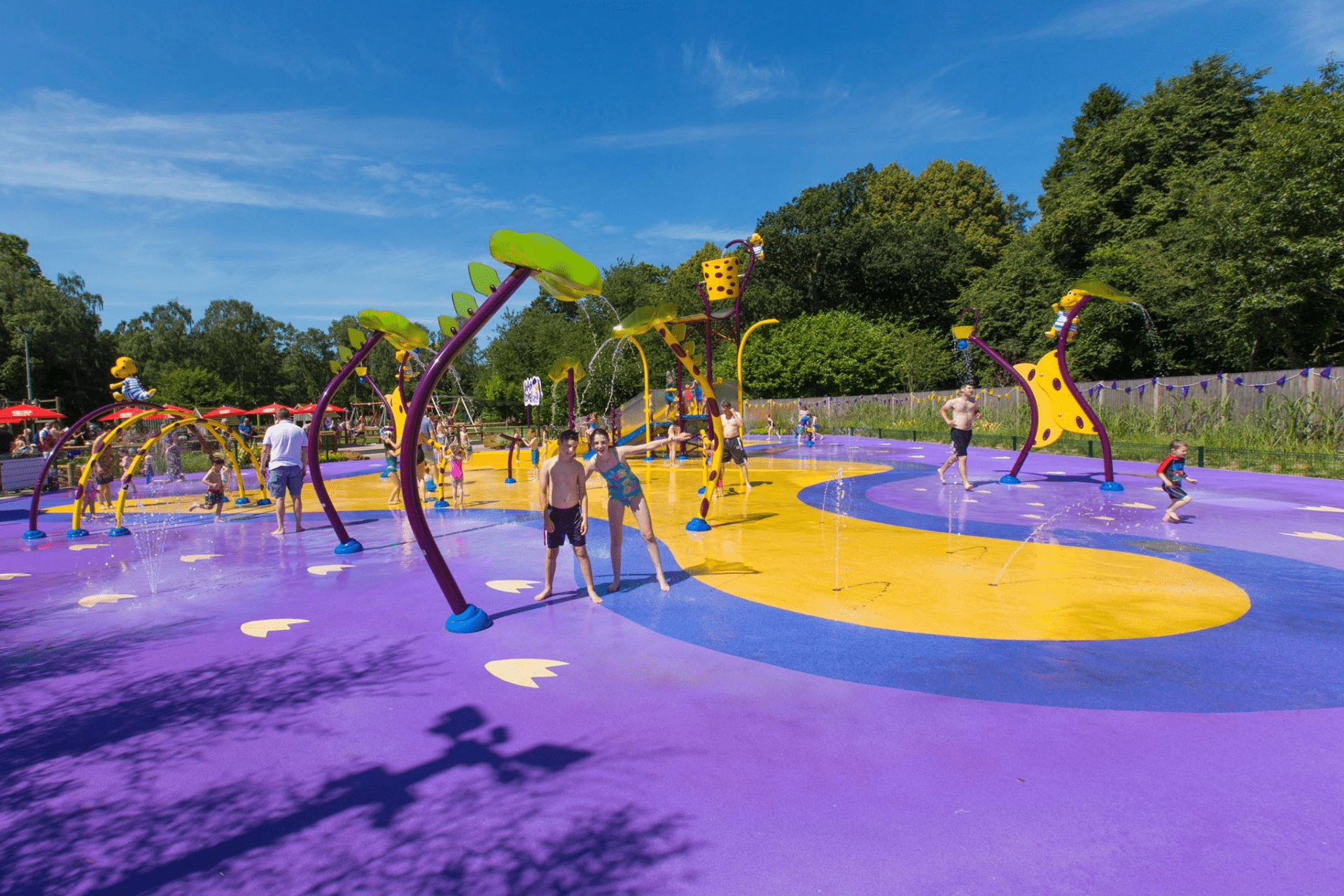 Children enjoying the outdoor splash park at ROARR! Dinosaur Adventure, with colourful water play zones and interactive fountains on a sunny day.