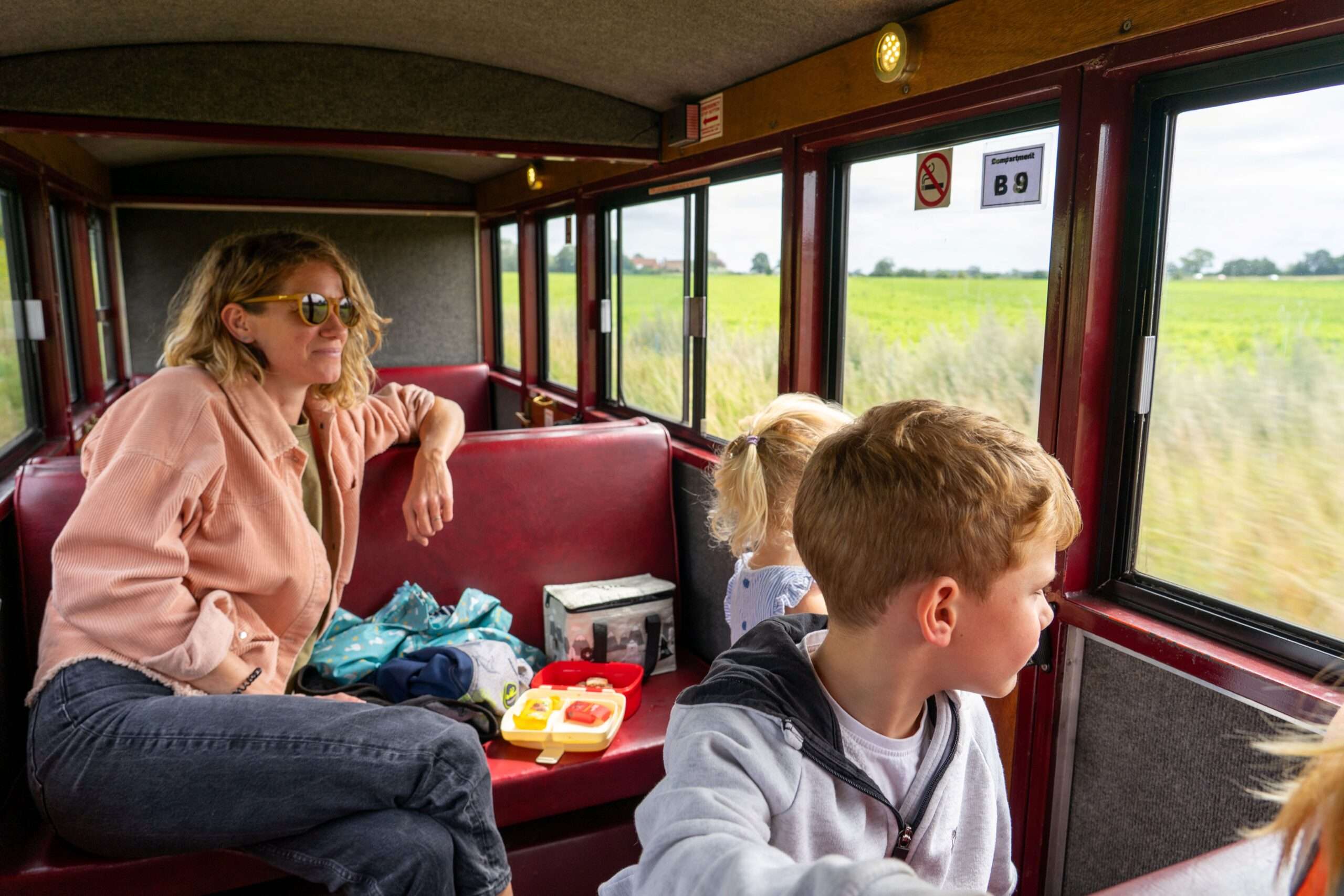 Passengers enjoying a journey aboard a Bure Valley Railway carriage, with views of the Norfolk countryside through the windows.