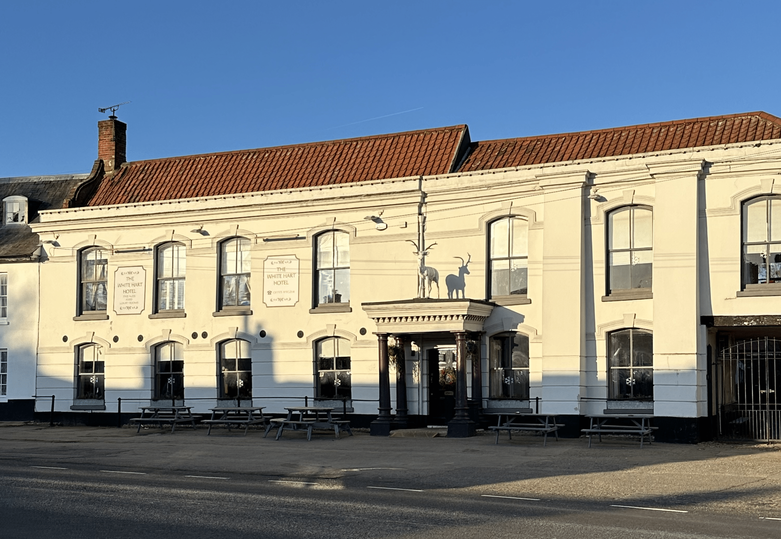 The White Hart public house exterior, featuring a large historic cream-coloured building with a traditional façade, sash windows and a prominent entrance on a village high street.