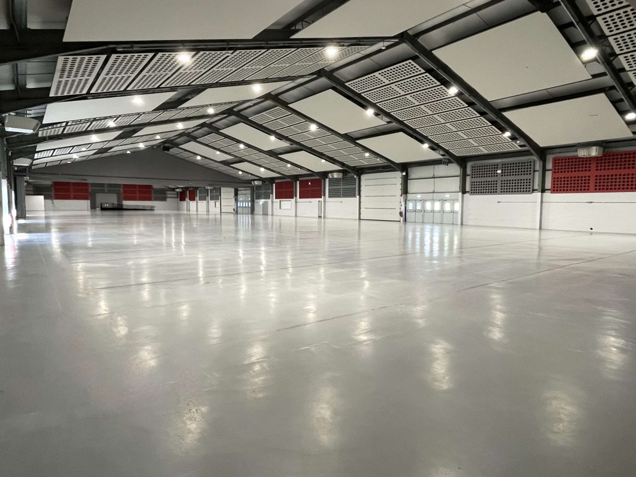 Large indoor exhibition hall at the Norfolk Events Centre with a spacious open floor, high vaulted ceiling, acoustic panels and bright overhead lighting.