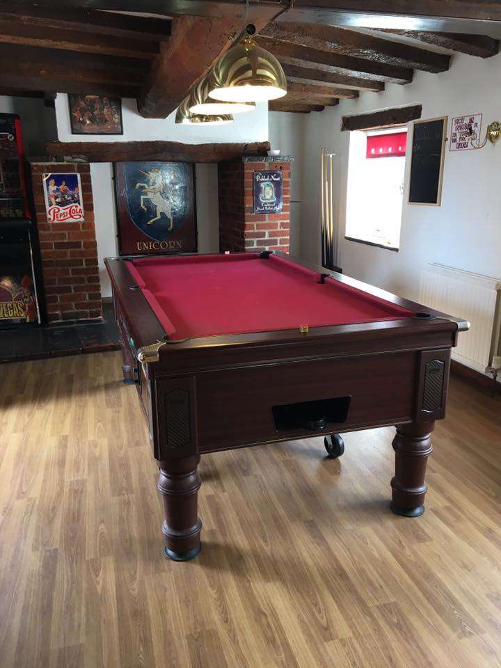 Pool table inside The Unicorn Aylsham, featuring a traditional pub games area with framed memorabilia and comfortable surroundings.