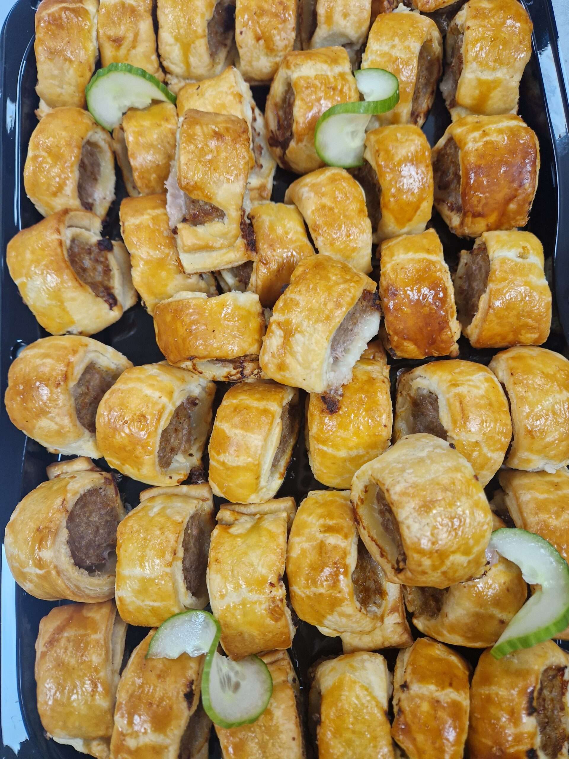 Golden-brown homemade mini sausage rolls neatly arranged on a serving tray.