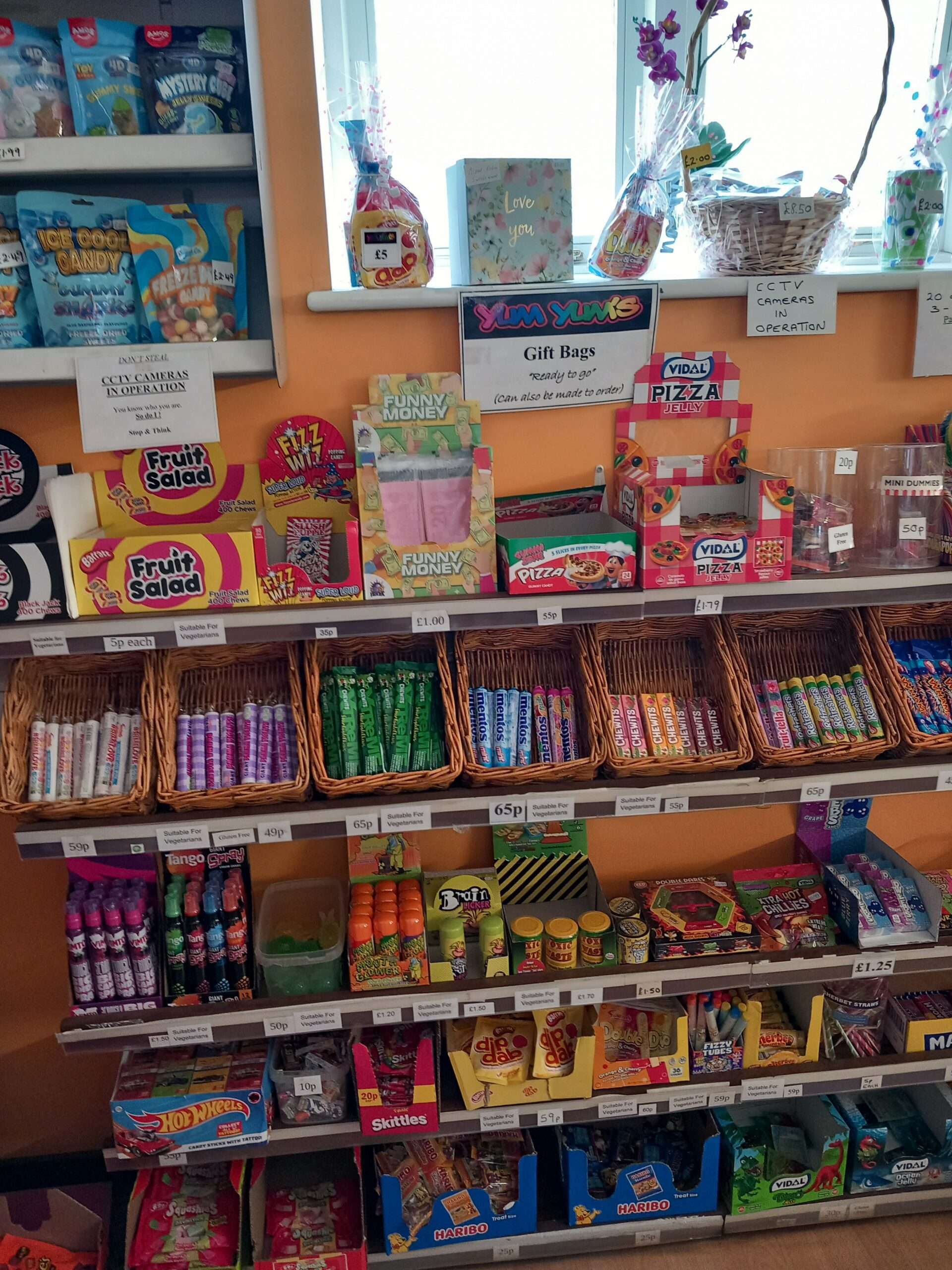 Sweet shop interior with books confectionery displayed on shelves and tables in a bright retail space.