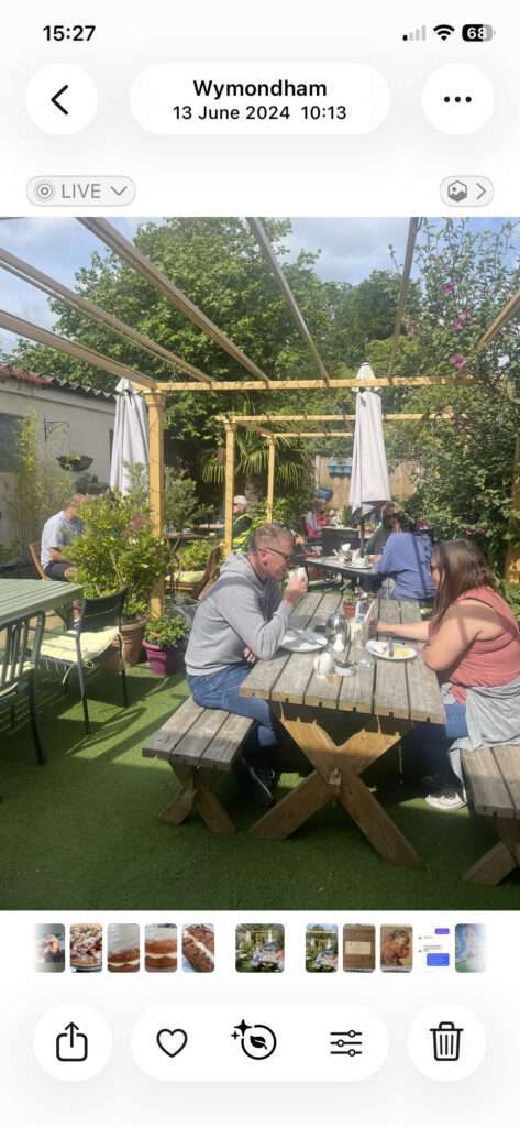 Visitors enjoying outdoor dining in a garden café surrounded by plants and flowers at Town Green Garden cafe