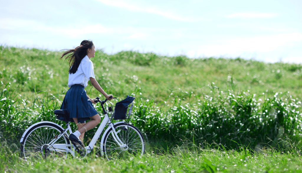 Cyclist riding across open countryside on a sunny day.