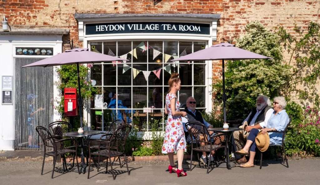 Entrance to Heydon Village Tea Room with outdoor seating and village shop-style frontage.
