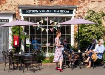 Entrance to Heydon Village Tea Room with outdoor seating and village shop-style frontage.