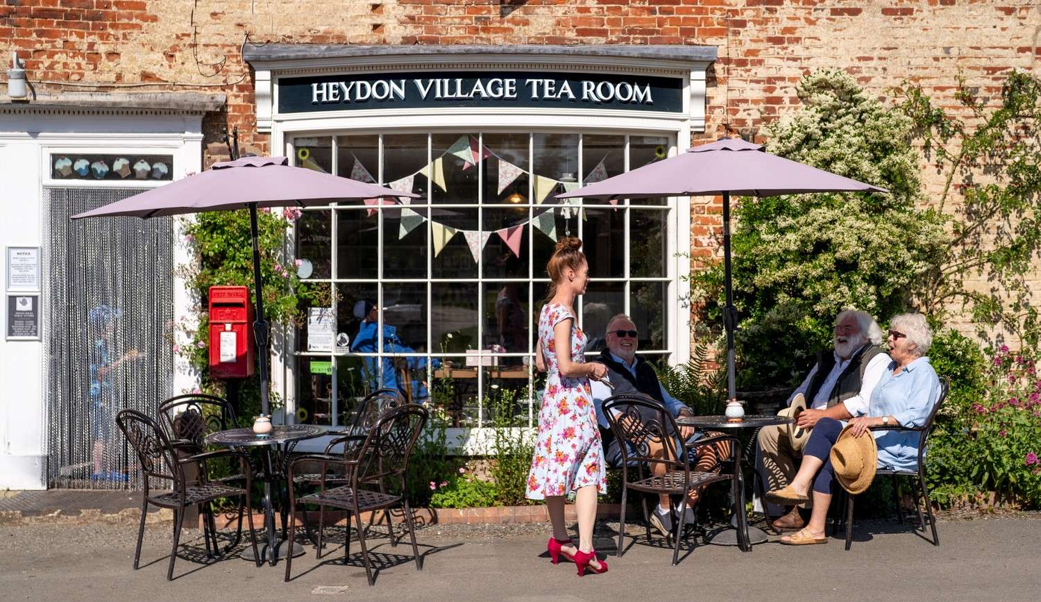 Entrance to Heydon Village Tea Room with outdoor seating and village shop-style frontage.