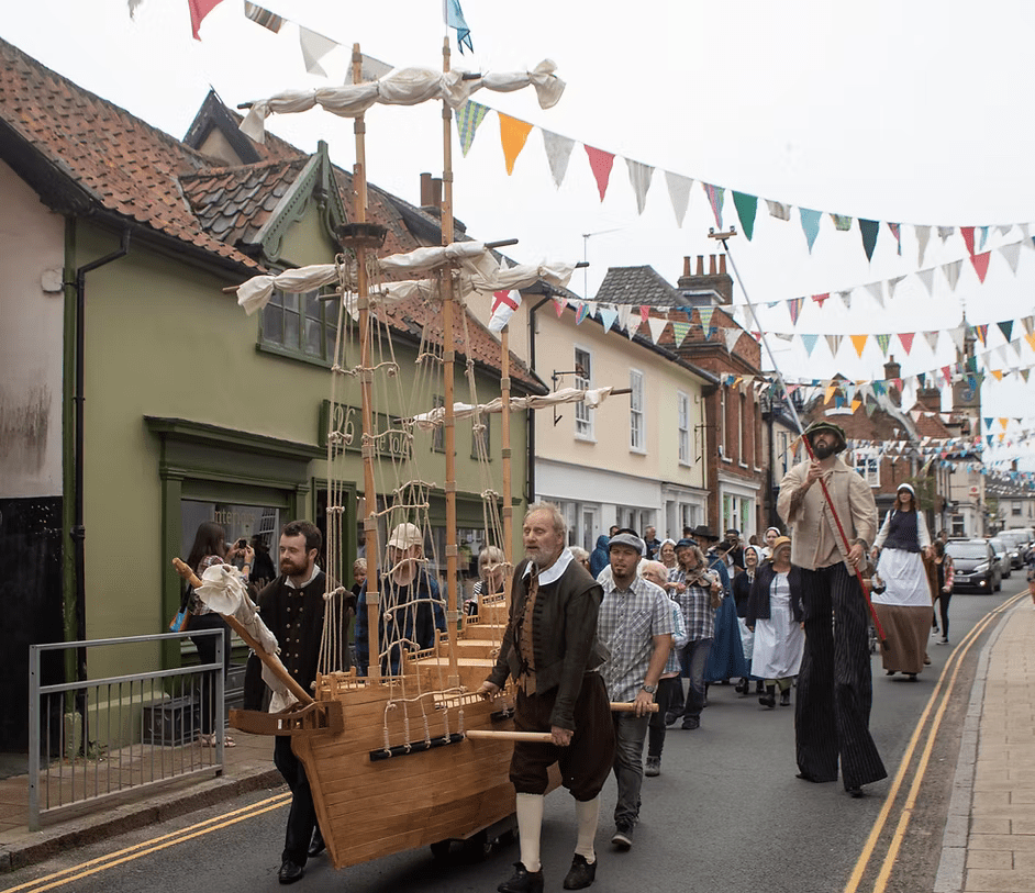 Street scene in Harleston decorated with colourful bunting during a community event, with historic buildings, visitors and the town’s characterful market town atmosphere on display.