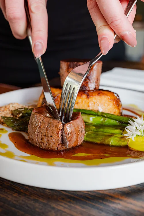 Close-up of a freshly cooked meat dish being served at The Huntsman, Strumpshaw, accompanied by vegetables and presented as part of the pub's dining offering.